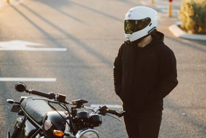 Portrait photo of a person wearing a helmet standing with a motorcycle